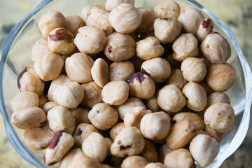Delicious peeled hazelnuts close-up in a glass bowl.