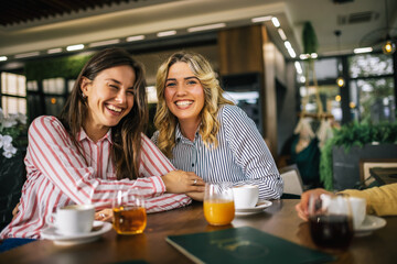 Two girl best friends talking and drinking coffee in a cafe.