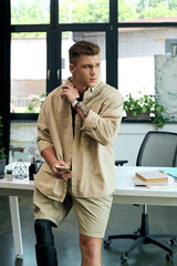 A young man with a prosthetic leg engages thoughtfully while working in a stylish office space.