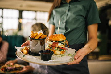 Delicious looking burger with fries and ketchup being served in a restaurant.