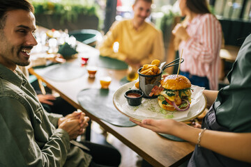 Waitress brings out the burger with fries to her customers.