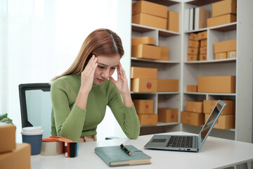 A woman is sitting at a desk with a laptop and a notebook