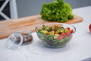 Full bowl of fresh green salad close up on a light table on a kitchen. Concept helpful and healthy food
