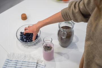 Close up of a woman making a smoothie with fruits and berries; selective focus. Healthy food concept.