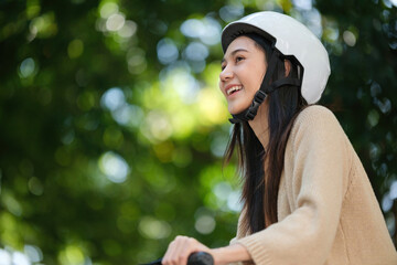 A woman is smiling while wearing a helmet and sitting on a bicycle
