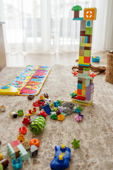 Colorful building blocks scattered around tall tower in bright playroom during daytime