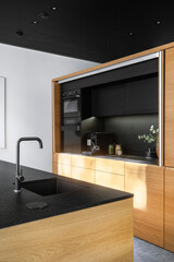 Modern minimalist kitchen design featuring sleek cabinetry and a black countertop in natural light