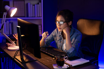 Stressful young beautiful asian creative looking on pc to search project creator social media online with planning channel strategy reach of more viewer home at neon modern office at night. Stratagem.