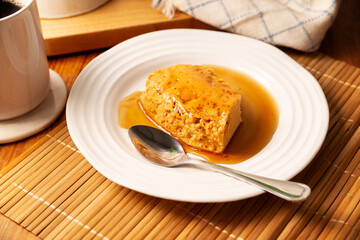 flan dessert, easy homemade recipe also known as creme caramel, caramel custard pudding or egg custard, served on white plate on wooden table.