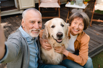 Active couple taking selfie vlogging with golden retriever on social media traveling by motor home
