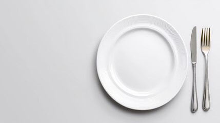 Elegant Table Setting: A minimalist overhead shot of a pristine white dinner plate with a knife and fork, perfect for restaurant menus, culinary blogs, or food-related designs. 