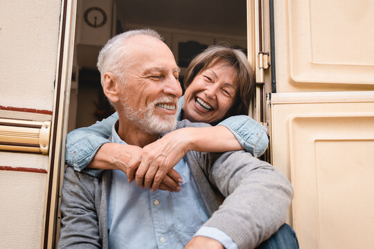 Grandparents hugging embracing together while traveling driving trailer camper van