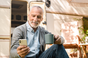 Confident caucasian senior old elderly man traveler explorer using cellphone for social media