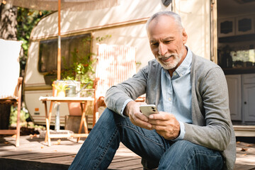 Cheerful old senior man businessman adventurer explorer using cellphone for online payment