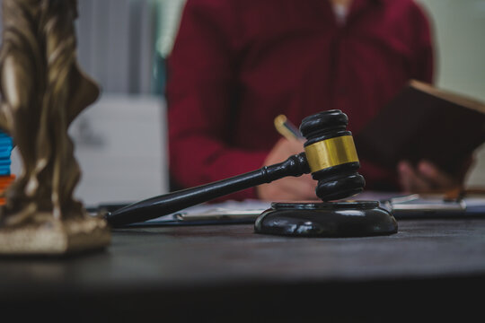An Asian male lawyer meticulously reviews legal documents, ensuring accuracy and compliance for an upcoming court case. He highlights key points and prepares strategies to effectively