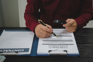 An Asian male lawyer meticulously reviews legal documents, ensuring accuracy and compliance for an...