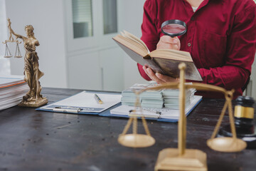 An Asian male lawyer meticulously reviews legal documents, ensuring accuracy and compliance for an...