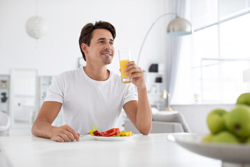 Good looking healthy man has breakfast at a table indoors.