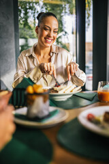 Beautiful woman eats lunch with her friends in a restaurant. She eats meat with salad.