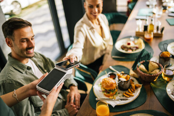People paying with contactless credit card in a restaurant.