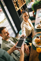 People paying with contactless credit card in a restaurant.