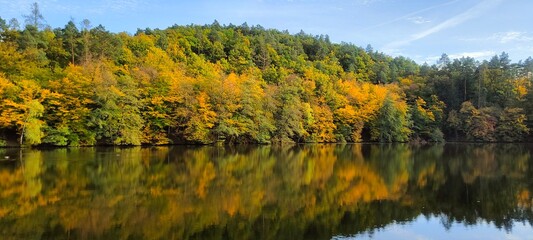 A lake with clear water, which reflects the autumn forest and sky, in the Czech Republic. Mariana Lakes