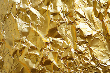Foil gold background with crinkled reflective surface and shimmering hue