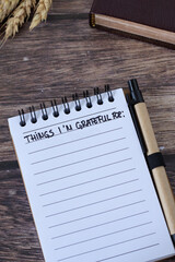Things I'm grateful for, handwritten text in notebook with holy bible and wheat on wood. Gratitude...