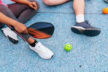 Multiethnic friends preparing to play pickleball on a blue court