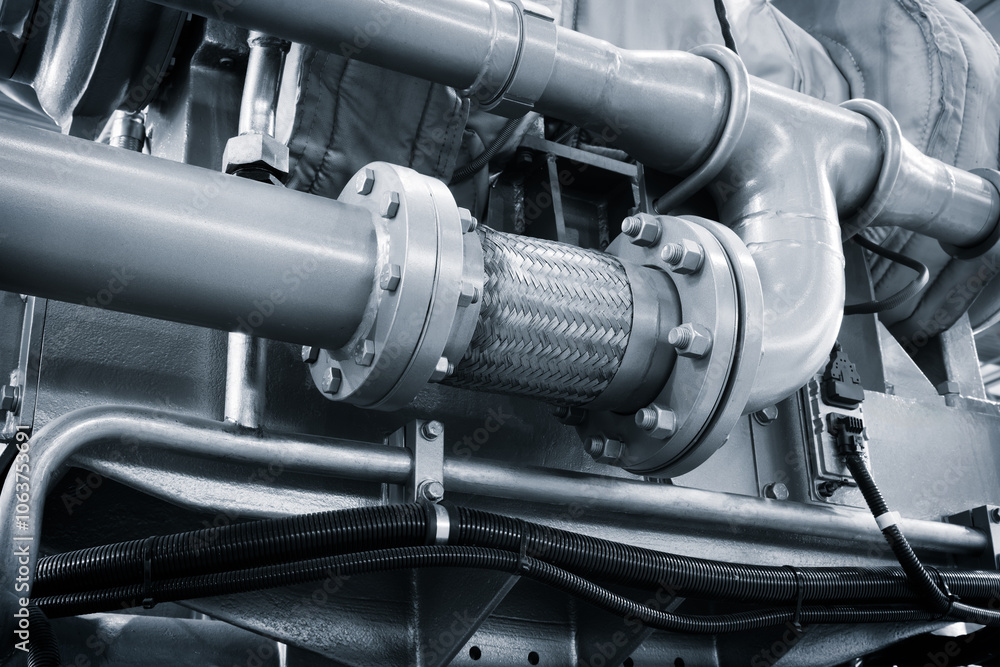 Poster A large engine with many parts is shown in a factory. The engine is made of metal and has a lot of pipes and valves. Concept of industrialization and the complexity of machinery