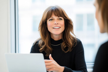 Cheerful businesswoman discussing in office with colleague