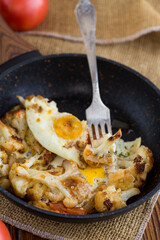 fried omelette with cauliflower and vegetables in a frying pan on a wooden table