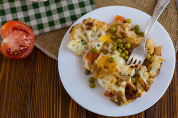 fried omelette with cauliflower and vegetables in a plate on a wooden table