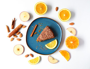 Creative layout made of carrot cake  with cinnamon sticks and oranges with lemon on the plate on the white background. Flat lay. Food concept. Macro concept. 