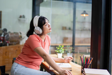 Intelligent young woman having online lessons on laptop, drinking coffee and taking notes,