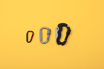 Different Types of Metal Carabiners for Climbing and Outdoor Activities Arranged on Yellow...