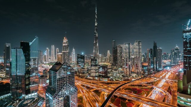 Timelapse view of iconic skyscrapers and traffic on major interchange at night in Downtown Dubai, United Arab Emirates (UAE). Modern cities and skylines, business and finance concept.