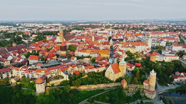 Drone wide-angle shot of Bautzen at sunset, capturing the historic cityscape bathed in warm, fading light. The scene highlights the town's iconic architecture and scenic skyline. Drone move right.