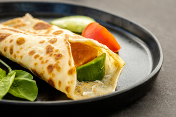Stuffed flatbread. The wrap contains salmon, avocado, and cream cheese on a black plate, accompanied by fresh salad leaves, tomato, and cucumber. Mindful eating, Balanced meals, nutrient-dense foods