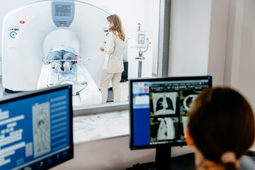 Doctor overseeing patient during CT scan in modern medical facility