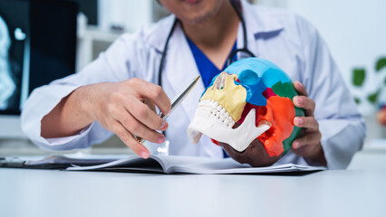 Professional senior doctor diagnose head pain or injury buy using a skull model to explain in hospital, Doctor is analyzing about brain tumor surgery, neurology examining. trauma or stroke discussion.