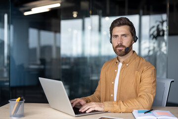 Mature business man using headset and laptop in office. Depicts professional communication, focus,...