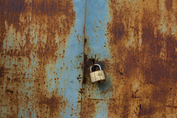 Rusty old metal doors are closed on a hinged lock.