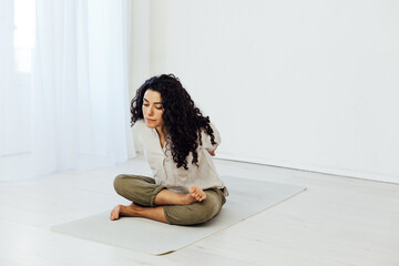woman doing exercises yoga asana in white gym