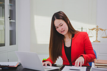 Asian businesswoman, focused , sits at ablack wooden table. Surrounded by notes , she strategizes her next move, embodying confidence and professionalism in her workspace.