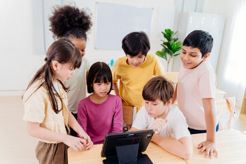 Diverse elementary students collaborate on digital tablet in modern classroom. Multicultural group engages in interactive learning, showcasing inclusive education and technological integration