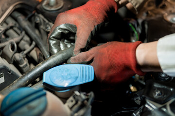 Obraz premium Hands of a Mechanic Repairing an Engine with Red Gloves