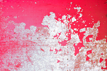 Red peeling paint on the grungy metal surface, metal background with peeling paint of red color