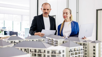 A real estate agent advises a client on the purchase of an apartment in a modern office modeled...