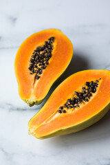  ripe papaya cut in half on a marble 